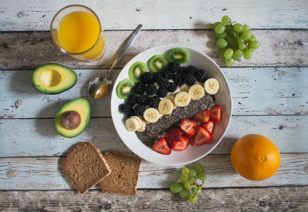 Learn the health benefits of eating fiber filled foods, like this bowl of chia, berries, and kiwi with whole-grain bread and avocado on the side.