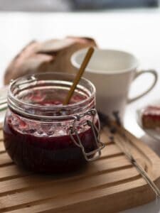 A jar of homemade fruit compote beside a mug