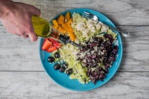 Someone adds olove oil, a healthy oil, to a freshly made salad