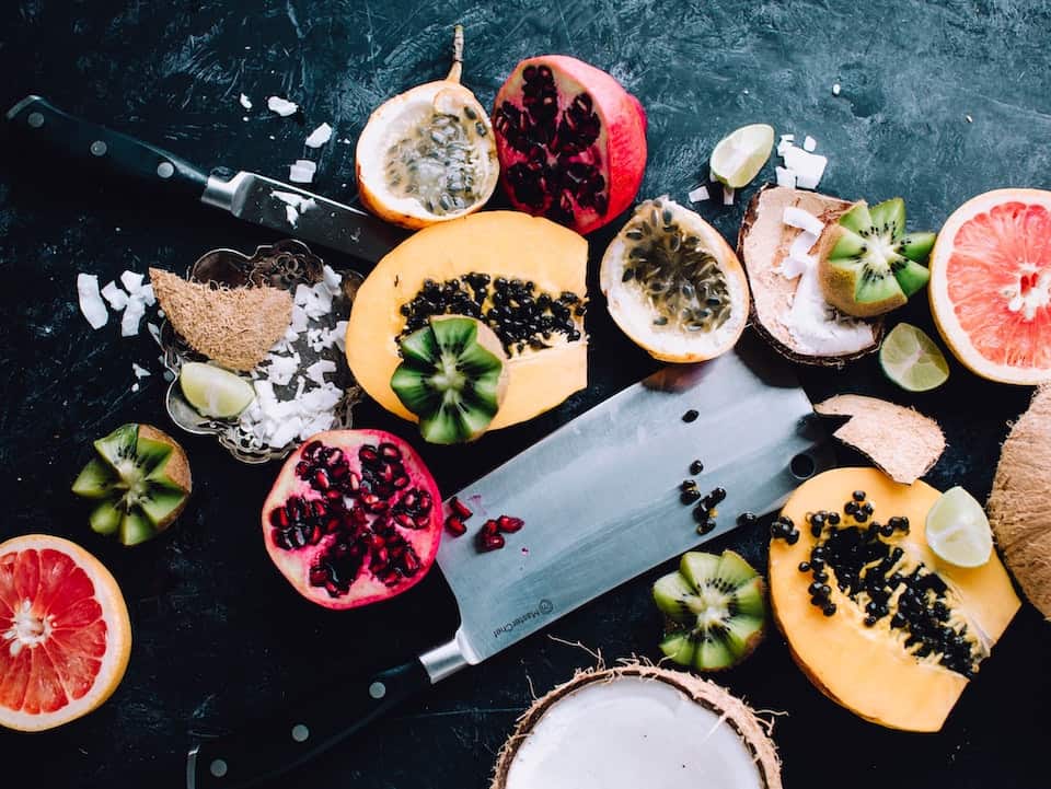 A variety of fruits cut open including pomegranate, melon, and grapefruit