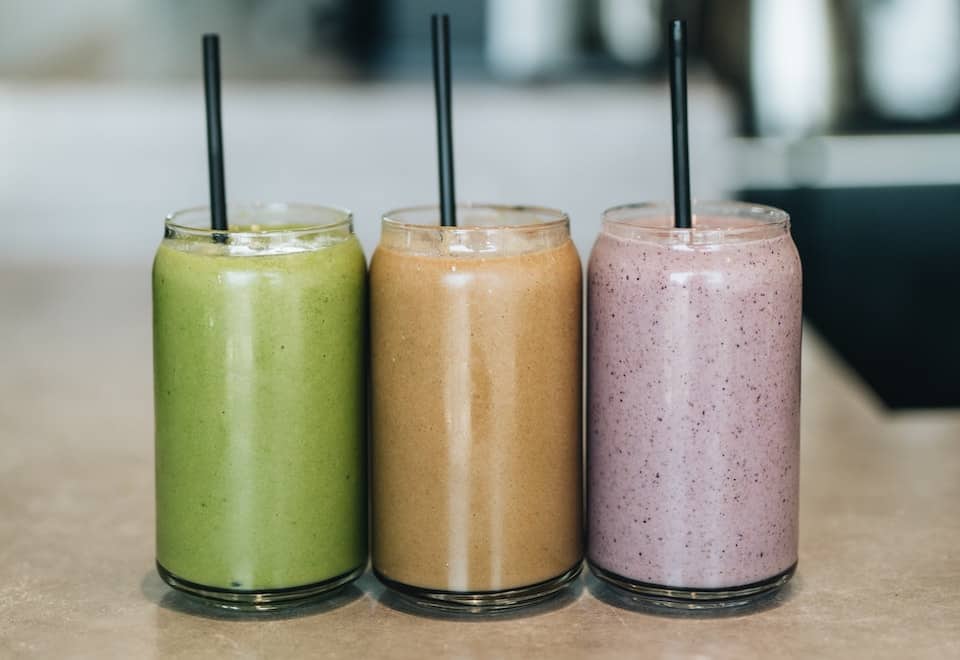 Three different colored smoothies in glass jars