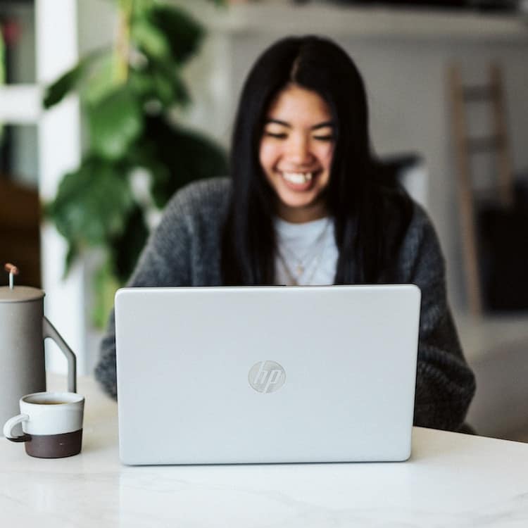 A woman smiles while on a video call on her laptop