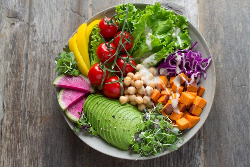 A colorful raw and cooling salad with avocado, greens, tomatoes