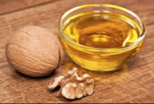 A walnut next to a small bowl of oil. Healthy diet includes essential fats