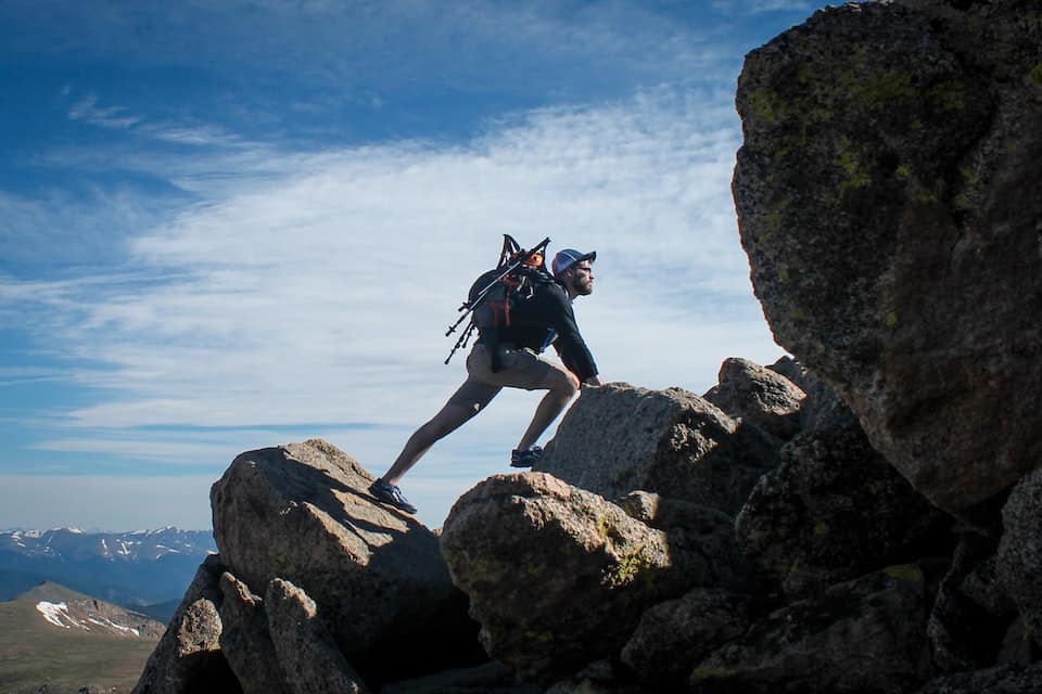 A man hiking up boulders, trying something new to add variety to his life