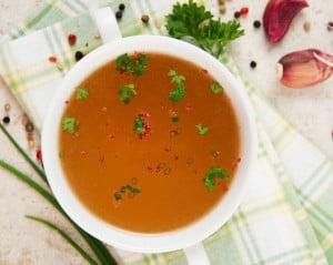 Bone broth, a superfood, in a white bowl garnished with parsley